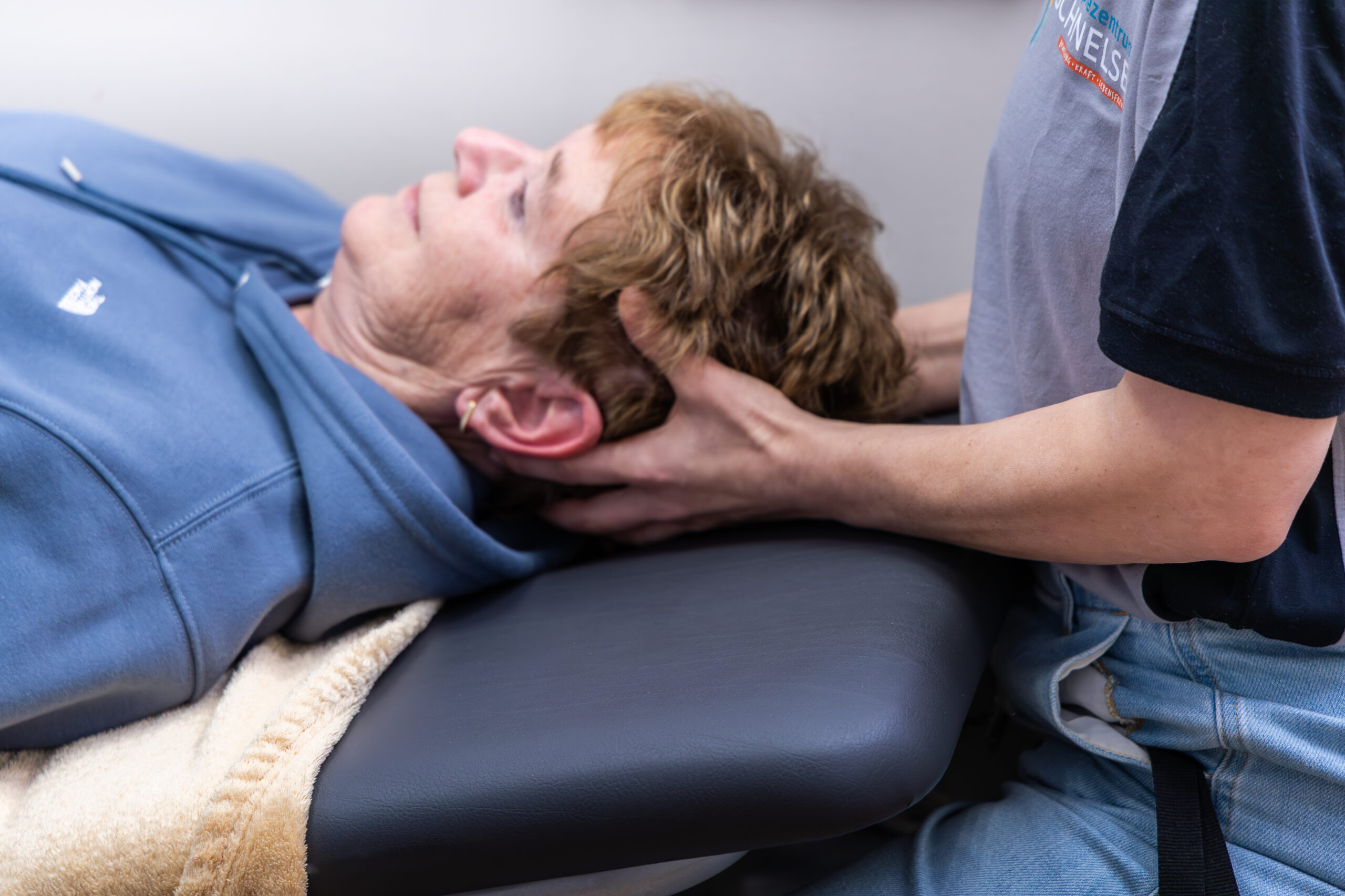 Therapeutin leitet eine Patientin bei einer Uebung mit dem Theraband an